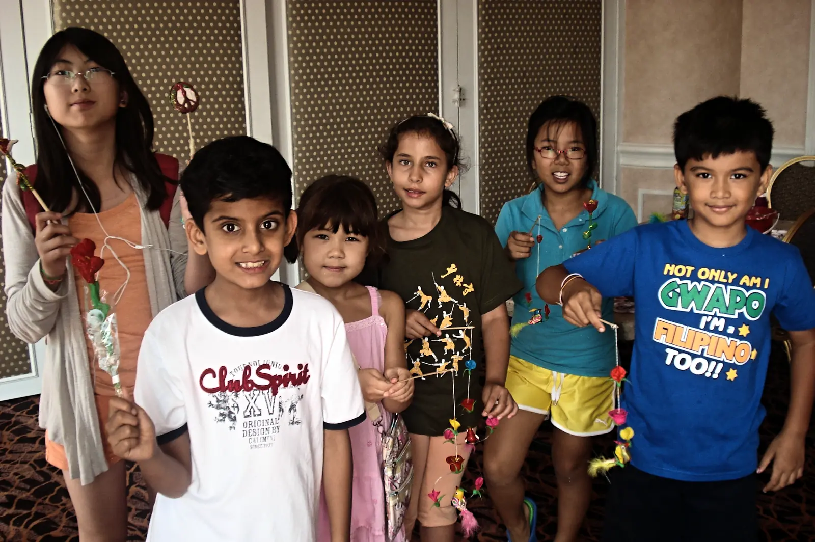 Young students holding up the paper and wire crafts they made in a culture activity