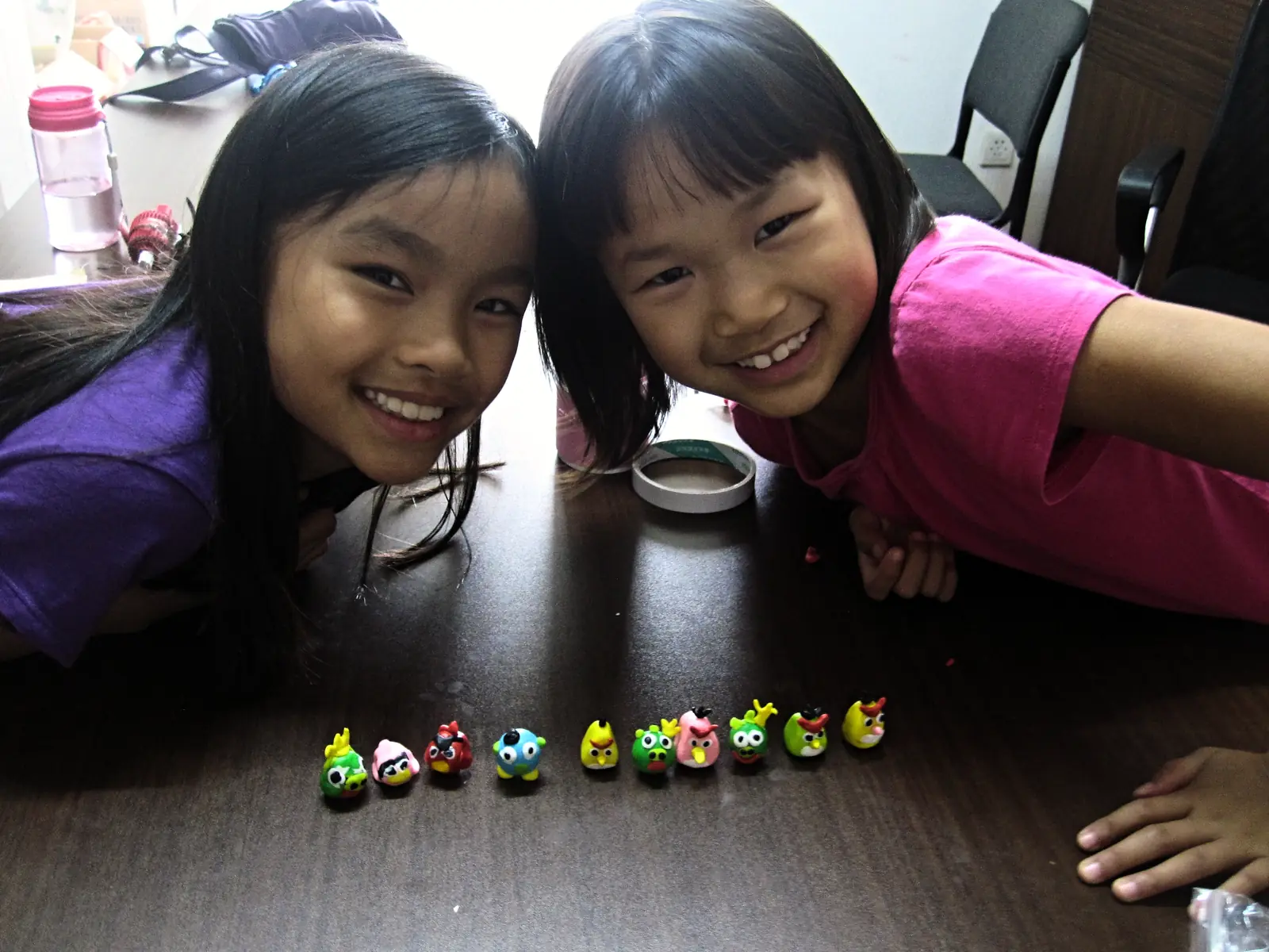 Two girls smiling over the row of stones they painted