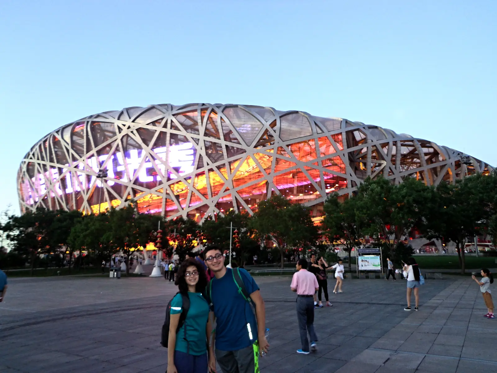 Students in front of the Bird's Nest stadium in Beijing, lit at dusk