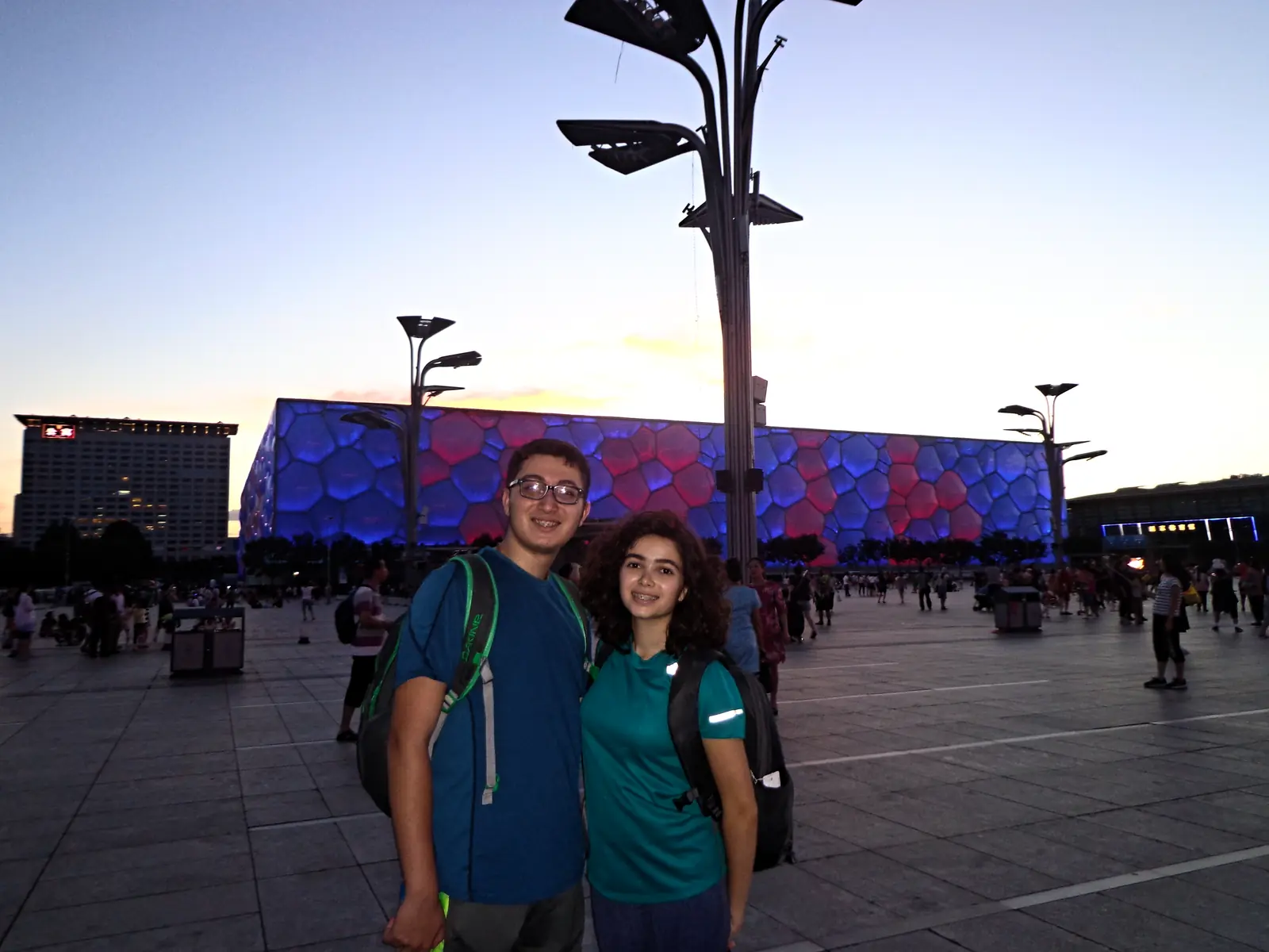 Two students in front of the floodlit Water Cube in Beijing