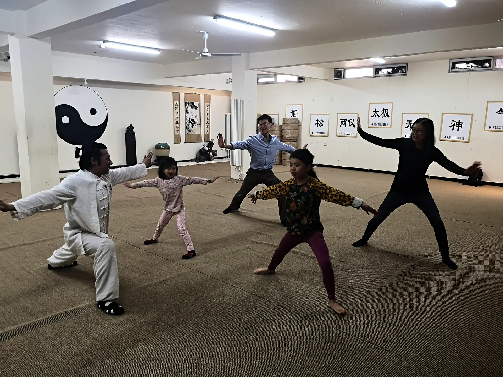 A tai chi session in the training hall beneath a taiji emblem