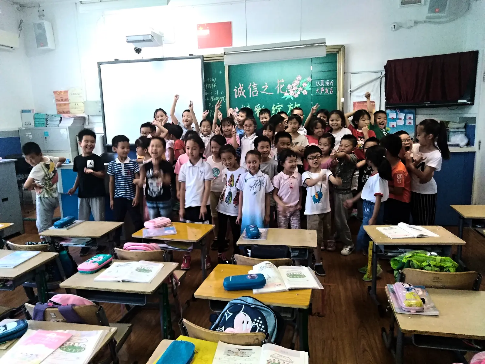 A Beijing primary class on their feet with hands raised, local and international children together