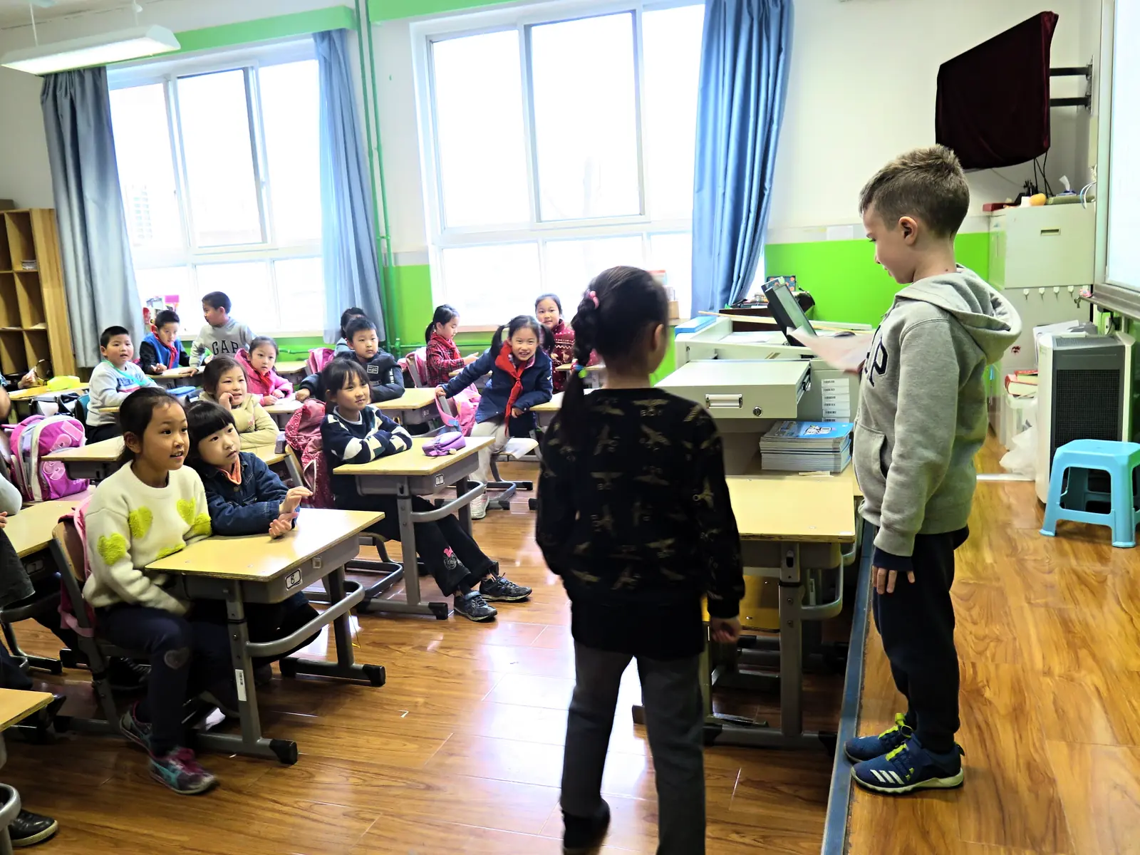 An international pupil standing among his seated local classmates in a Beijing primary school classroom