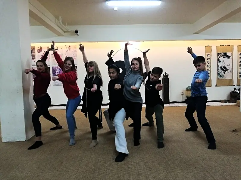 The group holding a wushu stance together in the training hall