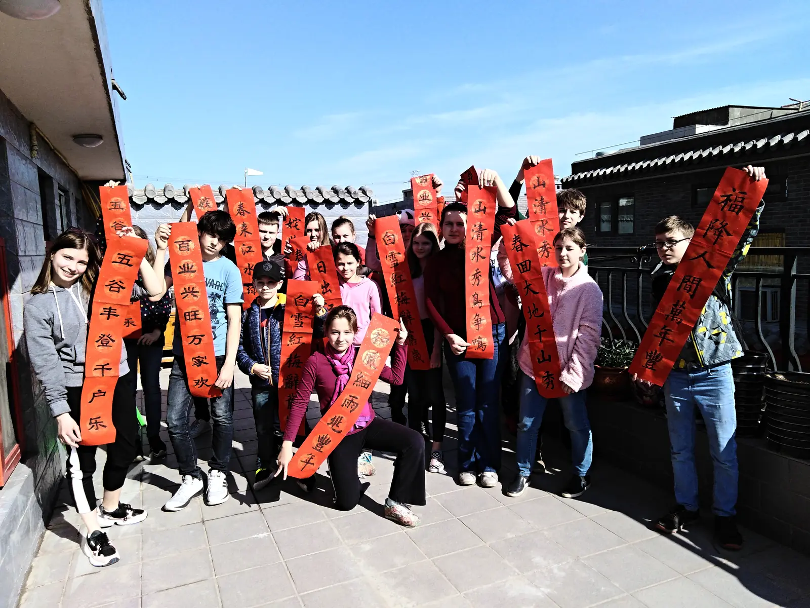 The group holding the spring couplets they wrote, courtyard roofs behind them