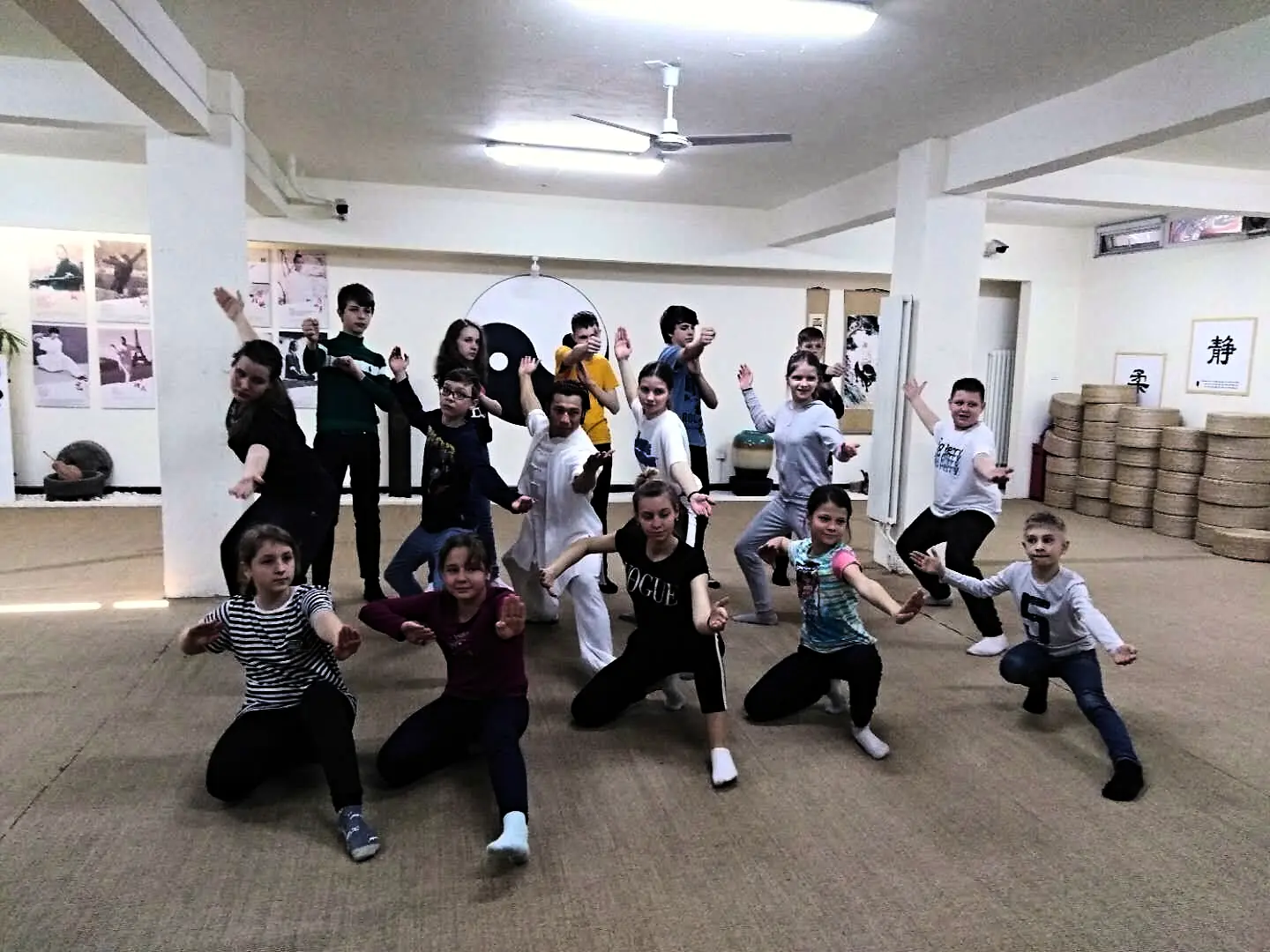 Students holding a low wushu stance across the floor of the training hall