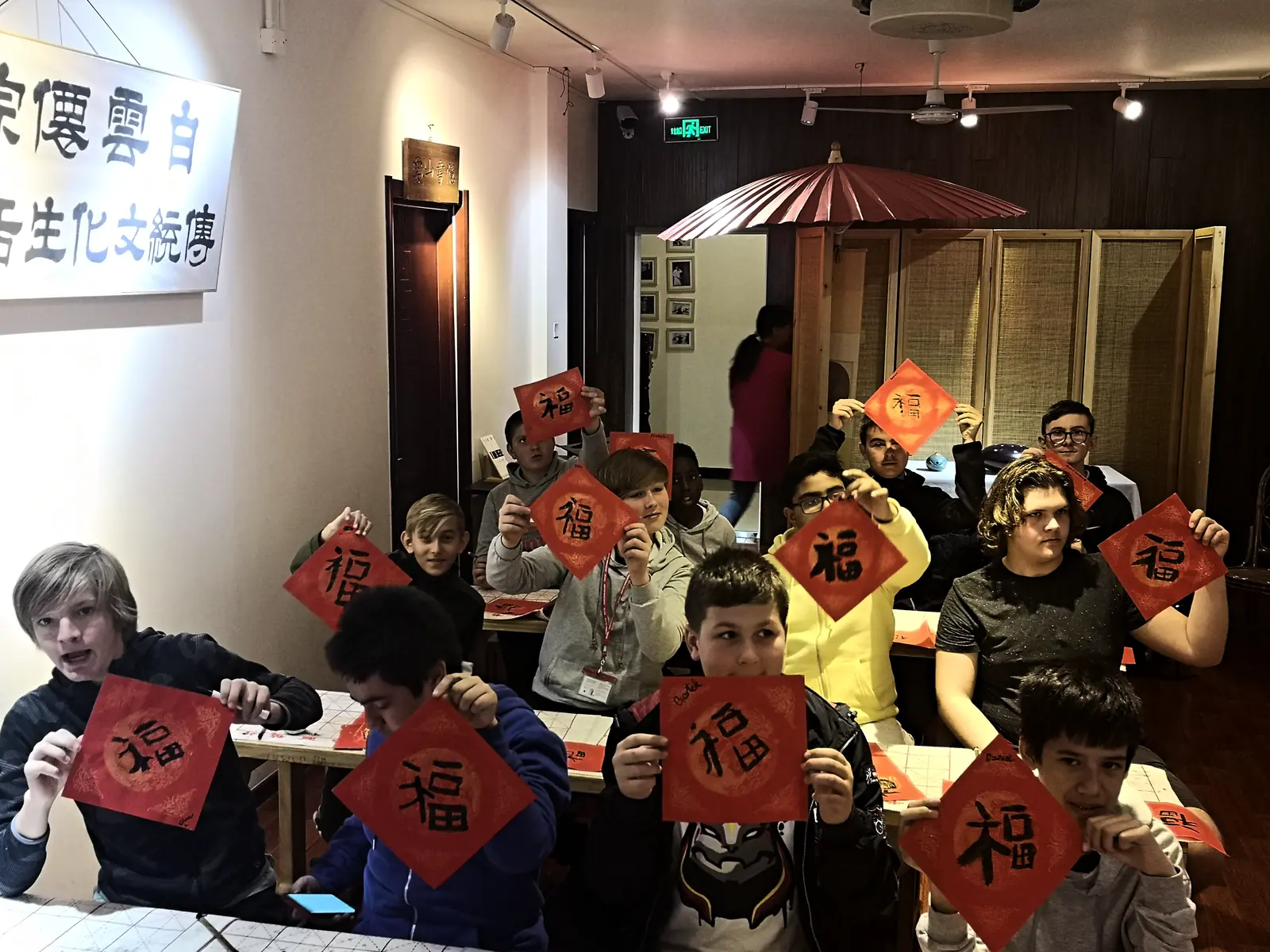 Students holding up the character 福 they brushed in a calligraphy class