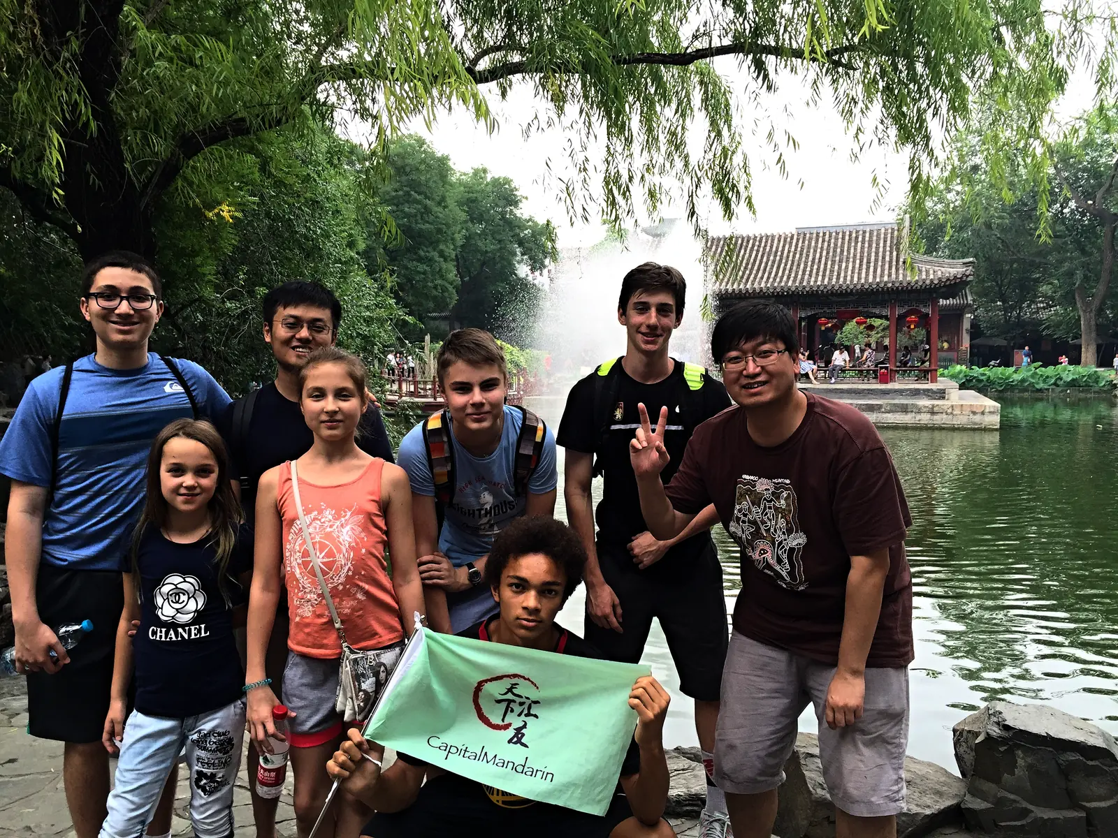 Campers by the lake at the Summer Palace with the school flag