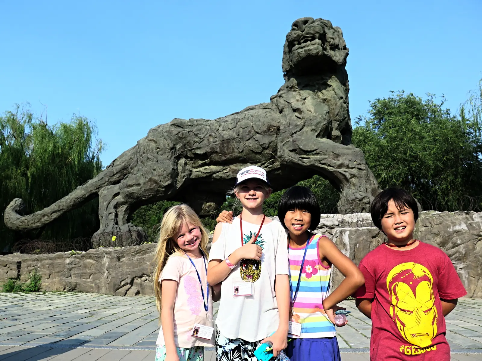 Younger campers beside a stone lion at the Summer Palace