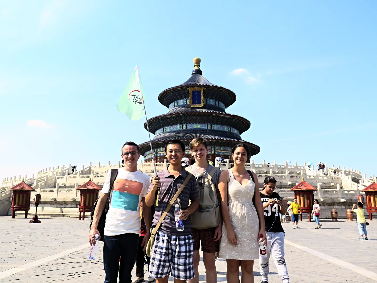 A camp group holding the school flag in front of the Temple of Heaven in Beijing under a clear sky