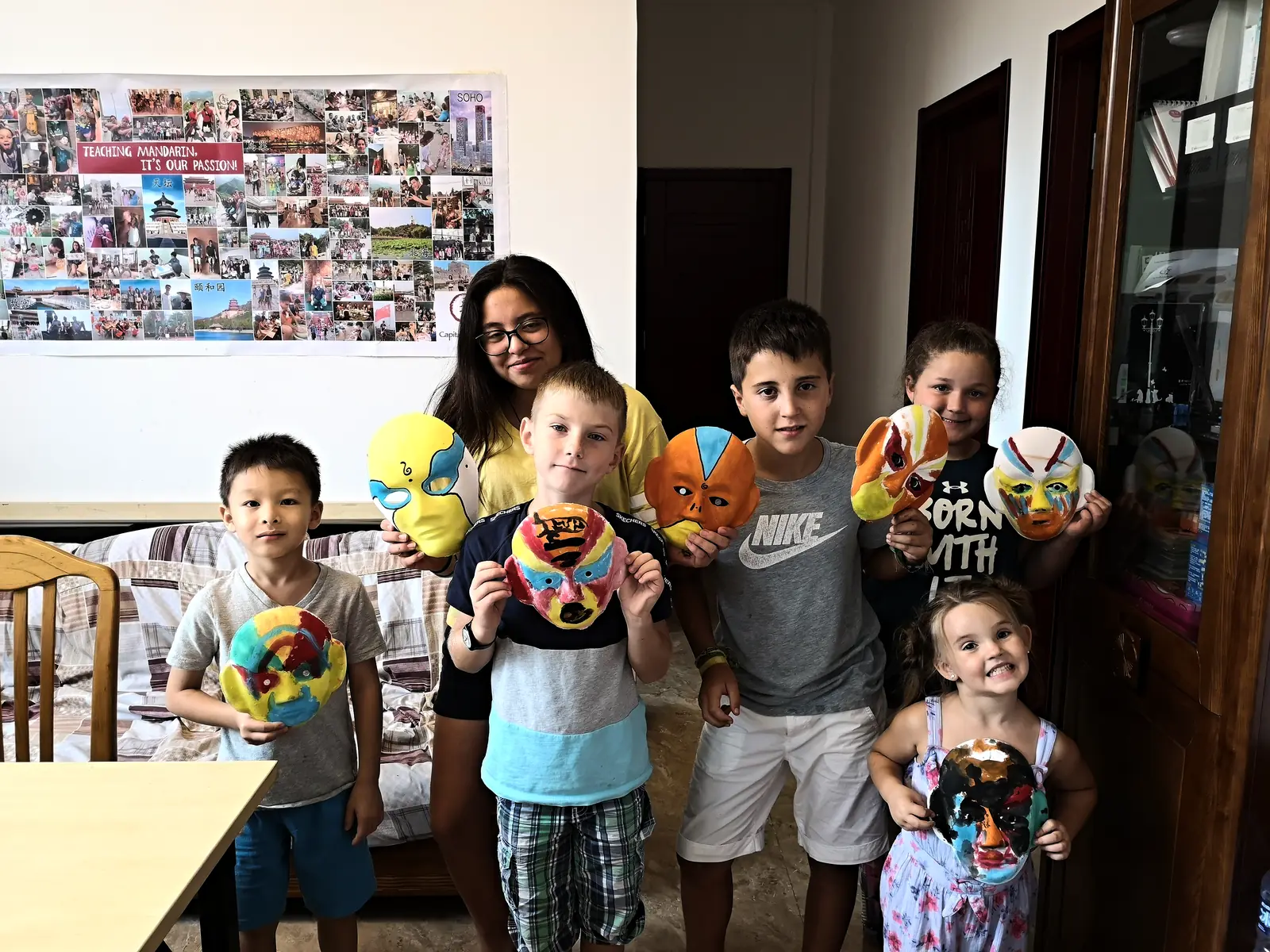 Campers holding up the Peking-opera masks they painted in a culture workshop