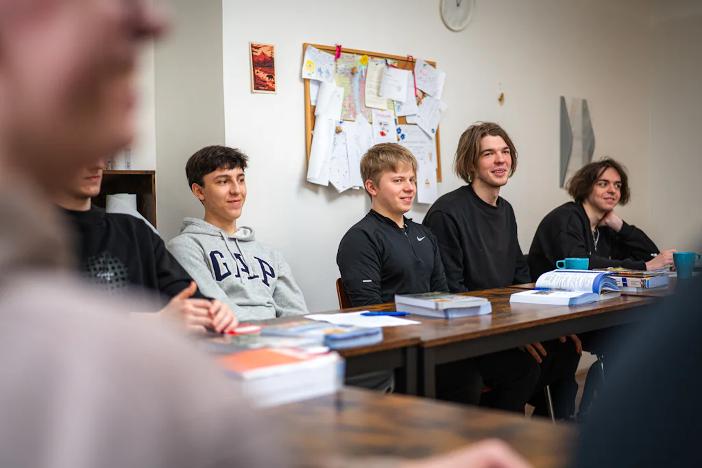 A small group of adult students around a classroom table with books and notes — stand-in for a photo of our own adult conversation classes
